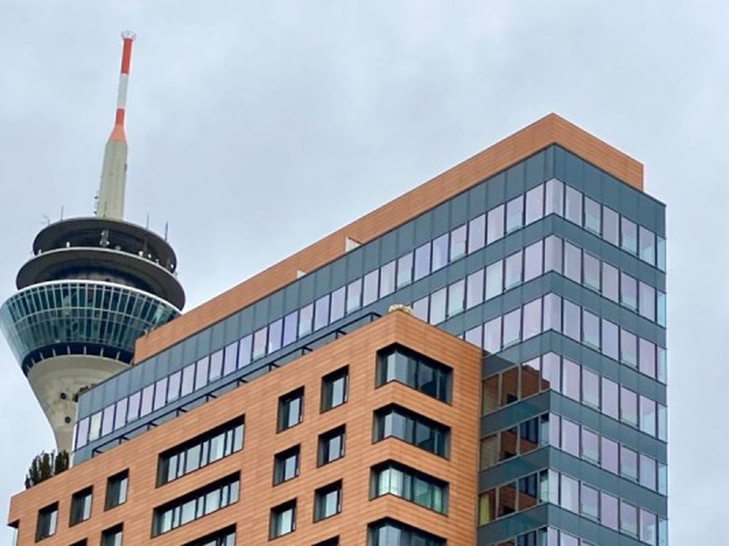 Eine Luftaufnahme von einem Gebäude über dem die Spitze des Rheinturms zu erkennen ist.