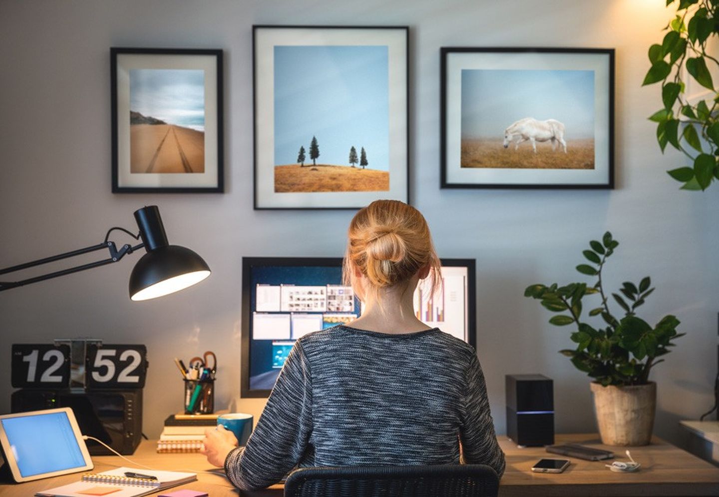 Energiesparen im Homeoffice: Eine Frau sitzt an ihren Schreibtisch vor einem Bildschirm, der seitlich mit wärmendem Lichtstrahl beleuchtet wird.
