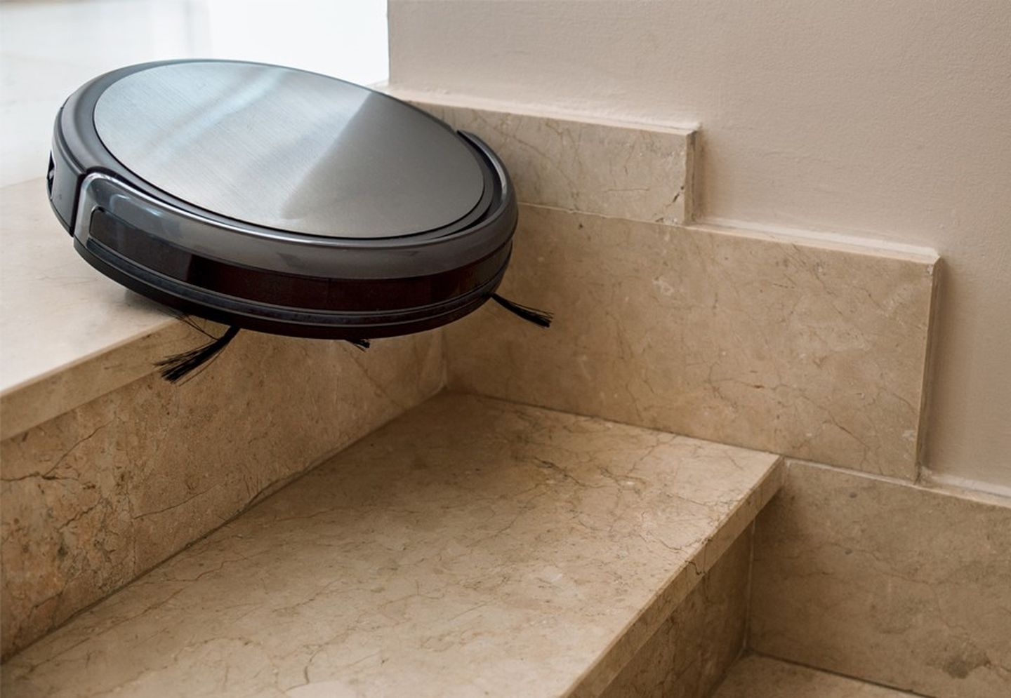 Ein Staubsaugerroboter fällt die oberste Stufe einer Treppe hinunter