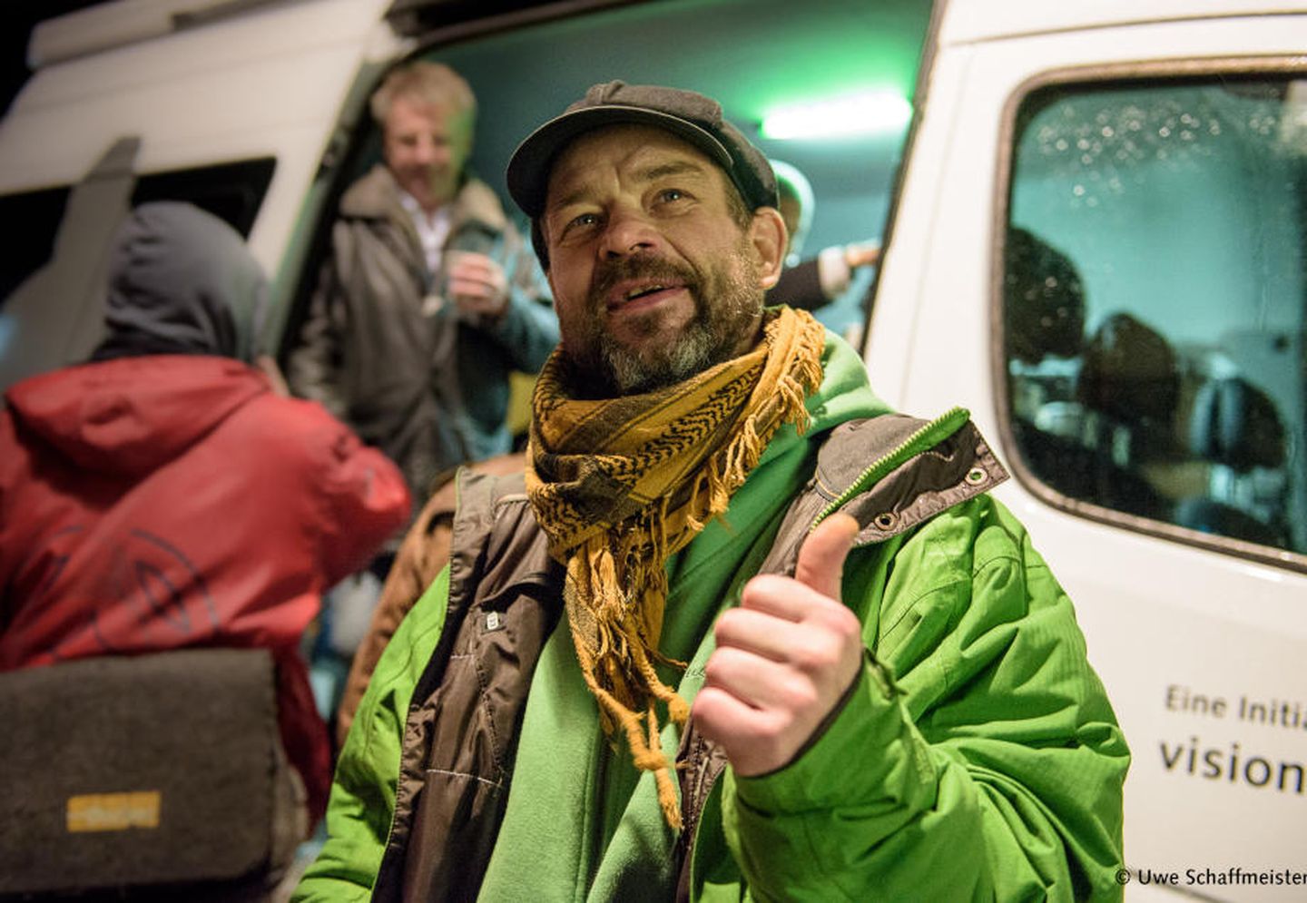 Ein Mann steht vor dem gutenachtbus in Düsseldorf und hält seinen Daumen hoch.