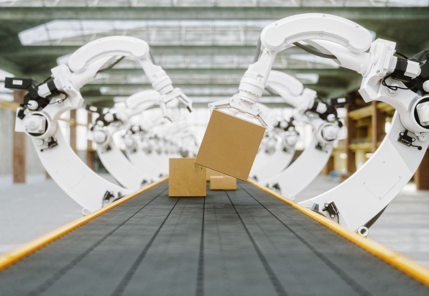 Eine Fabrik mit vollautomatisierter Produktionsstätte, an der Roboterarme Kisten greifen.