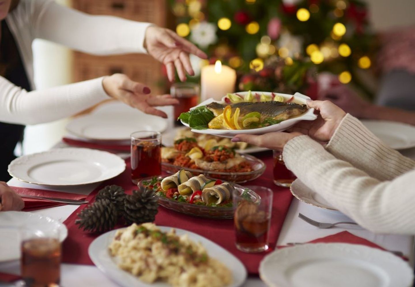 Weihnachtsbräuche: traditioneller Weihnachtskarpfen wird am gedeckten Weihnachtstisch überreicht