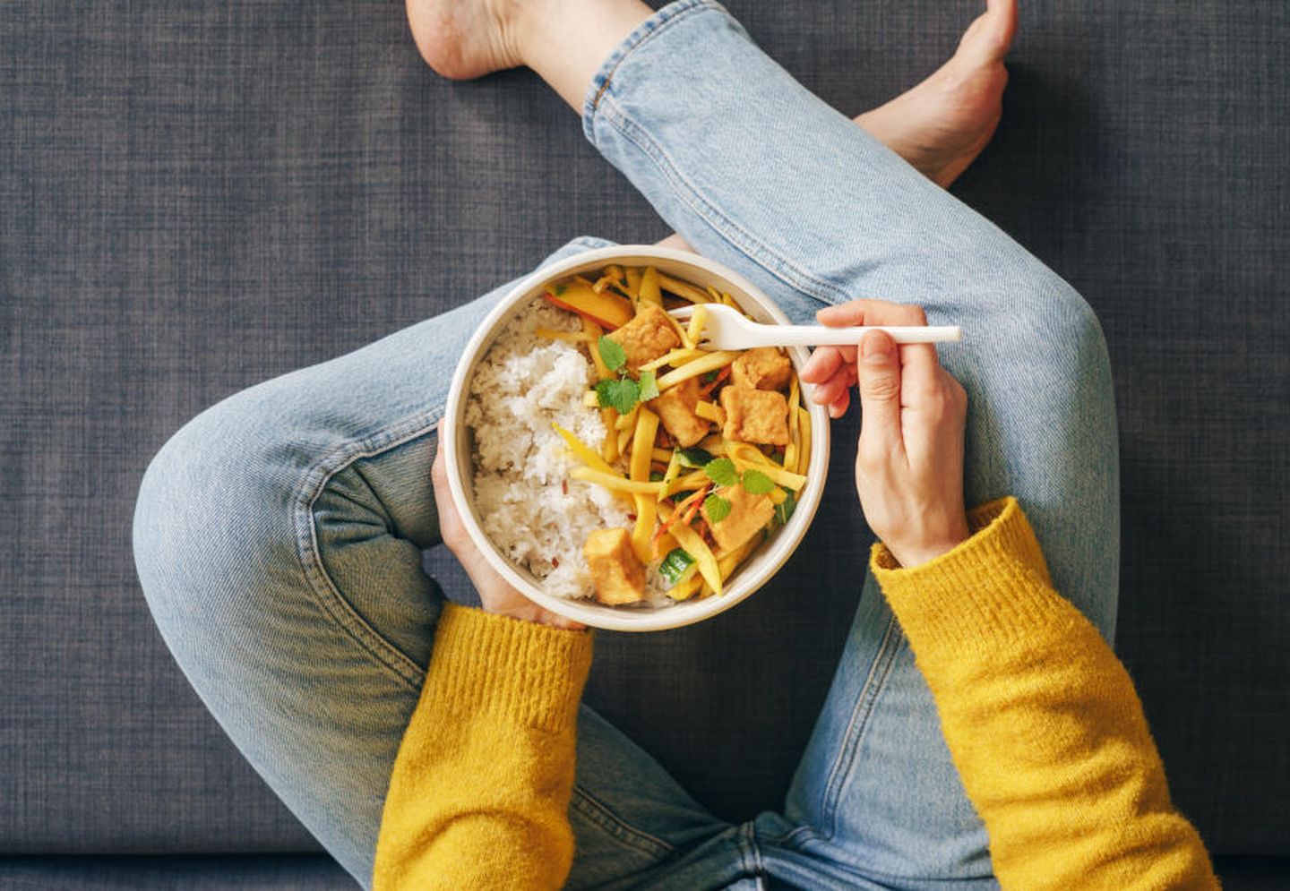 Eine Frau isst ein Currygericht aus einer Mehrwegverpackung. © Xsandra / E+ via Getty Images
