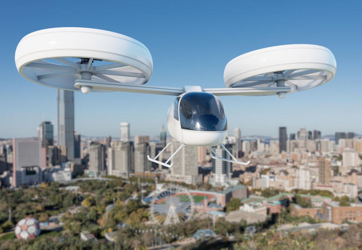 Ein Flugzeugtaxi-Prototyp fliegt über die Dächer von Wolkenkratzern einer Stadt. © z FL / Moment via Getty Images