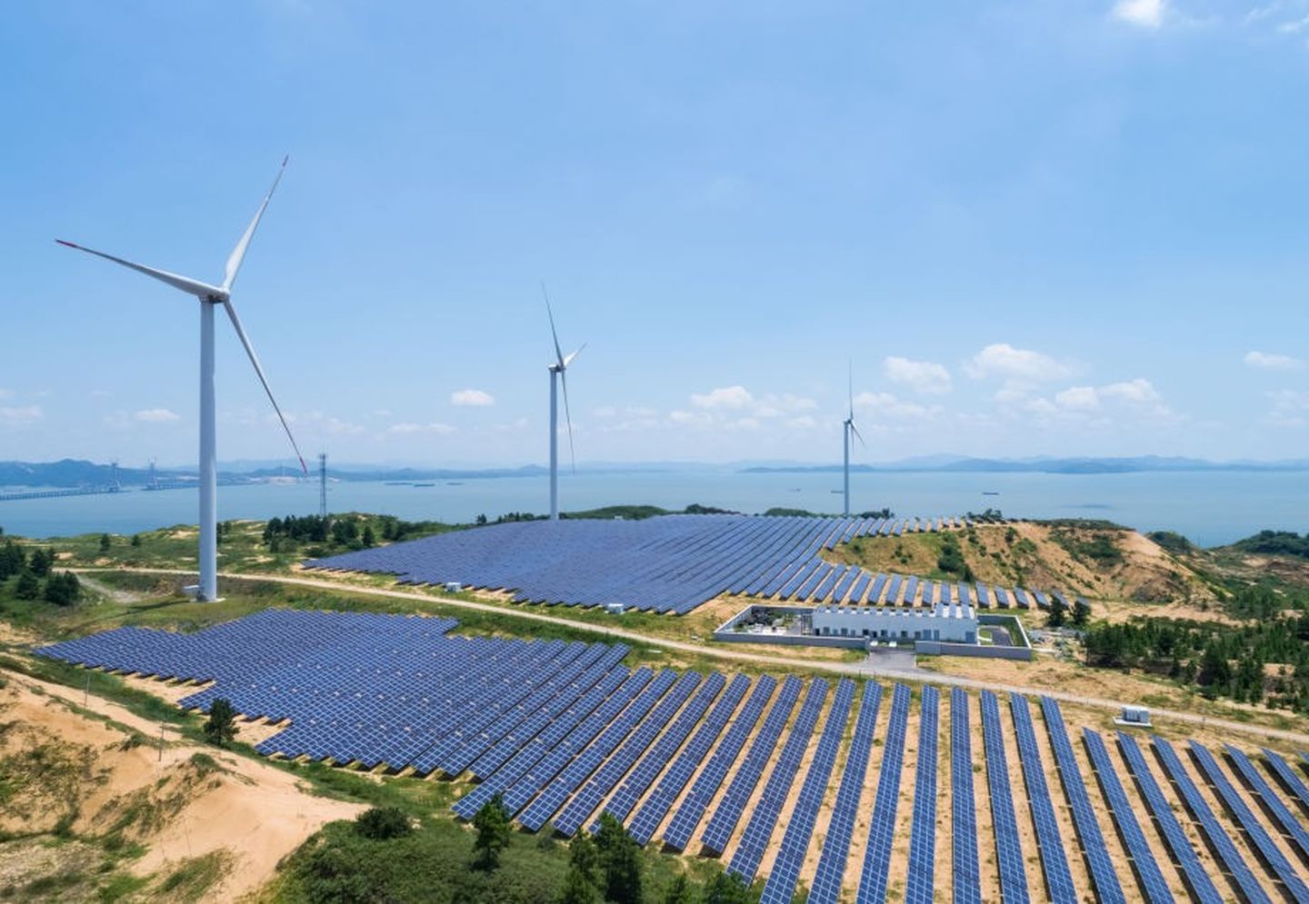 Windkraft- und Solaranlage neben einem großen Gewässer