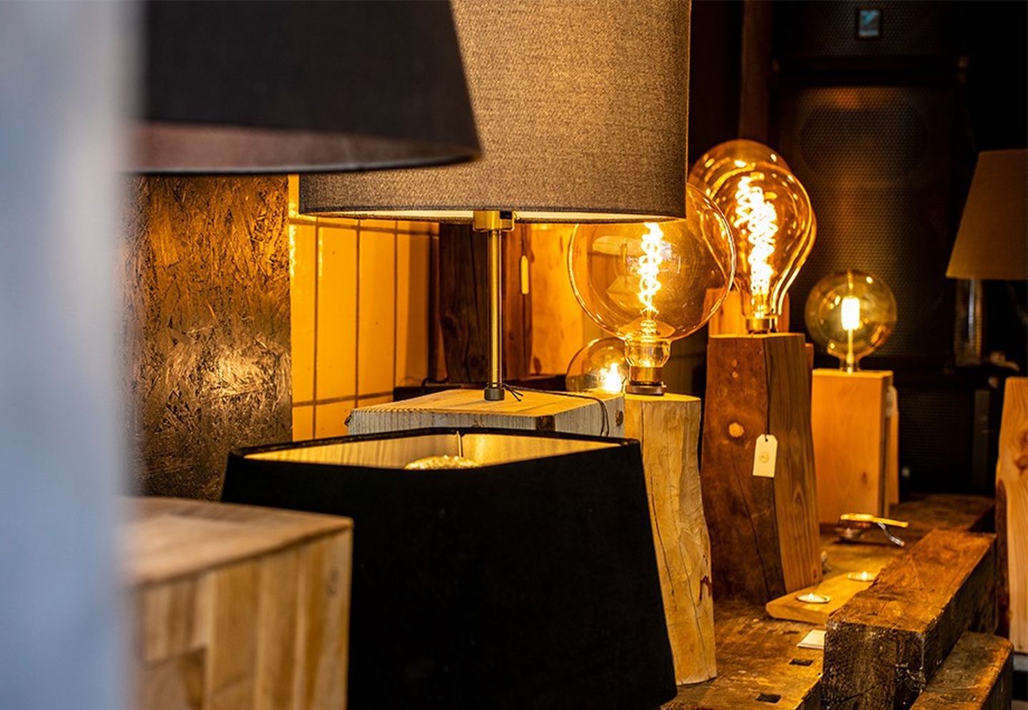 Leuchten aus Holz mit Retrofit-Lampen in Glühbirnenoptik stehen in einer Reihe mit Lampenschirmen in gedeckten Farben.