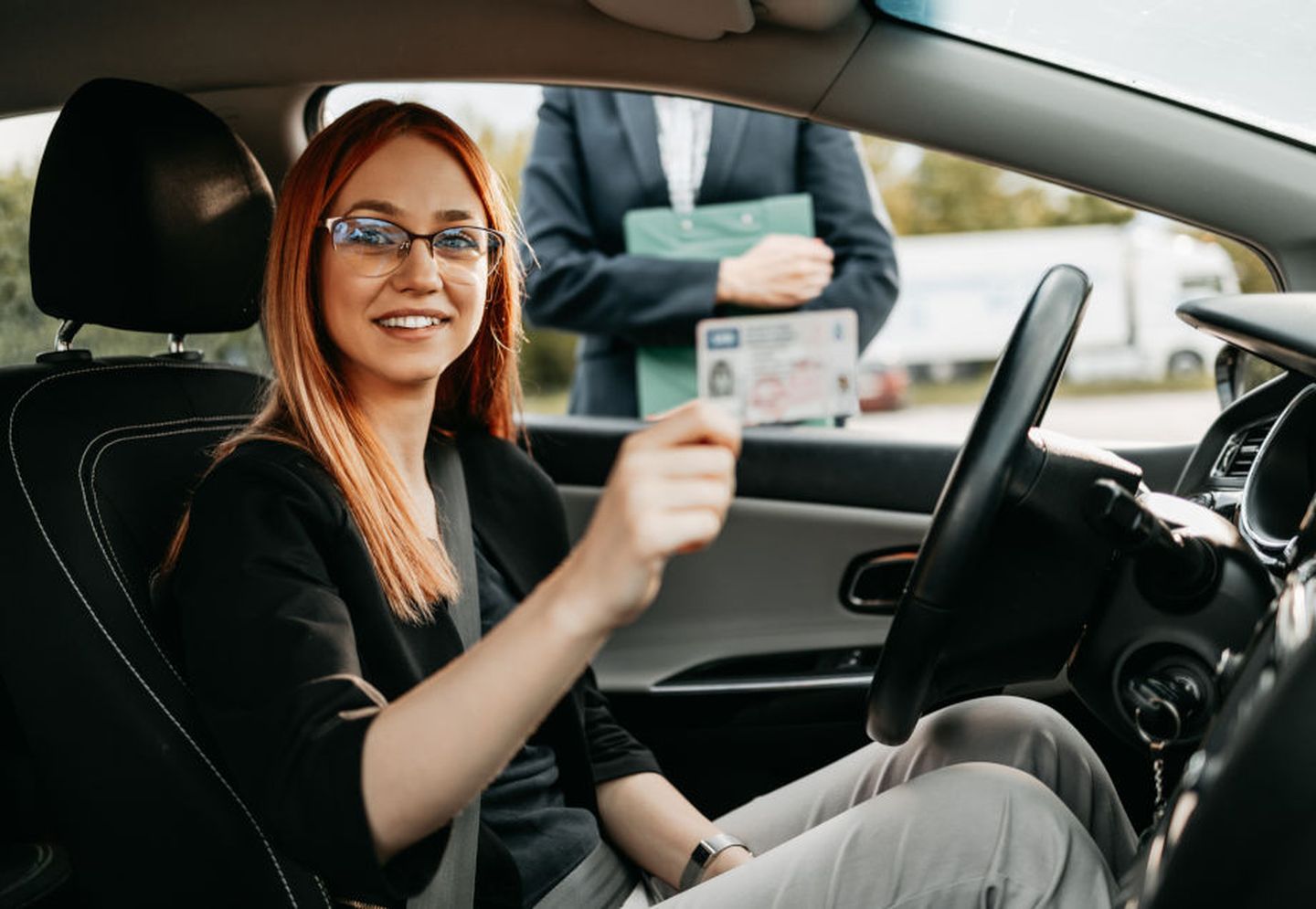 Fahrschule mit E-Auto: Fahrschülerin hält ihren Führerschein in der Hand