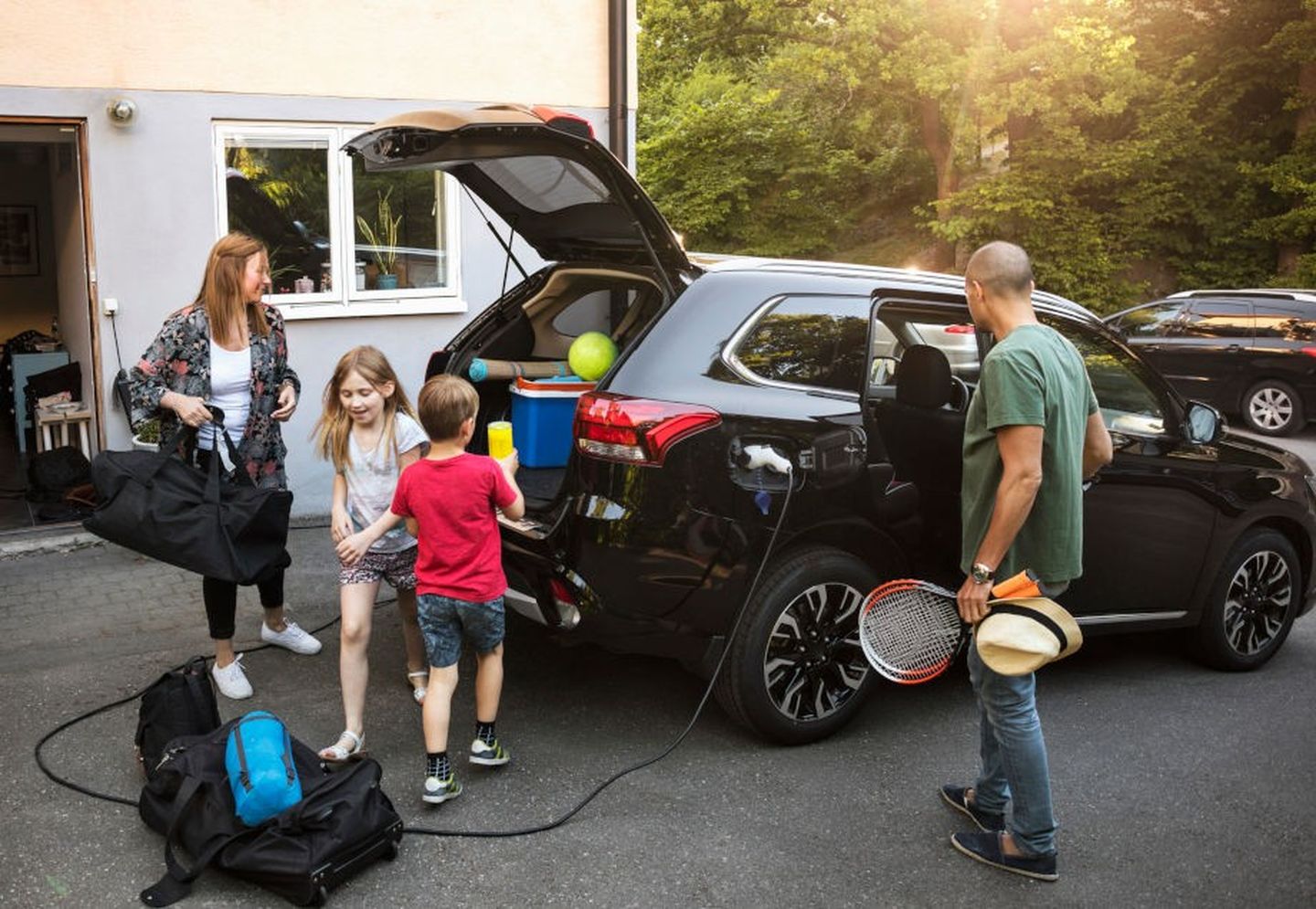 Eine Familie lädt ihr E-Auto neben der Garage auf. © Maskot via Getty Images
