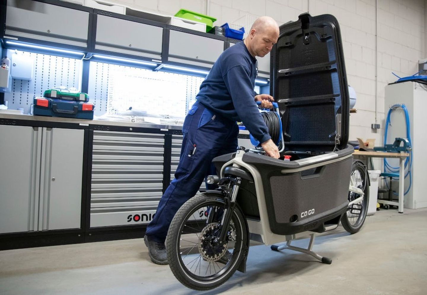 Handwerker befüllt sein E-Lastenrad in der Werkstatt