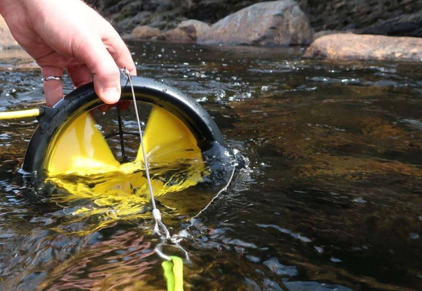 Eine Miniturbine wird in einen Fluss gehalten.