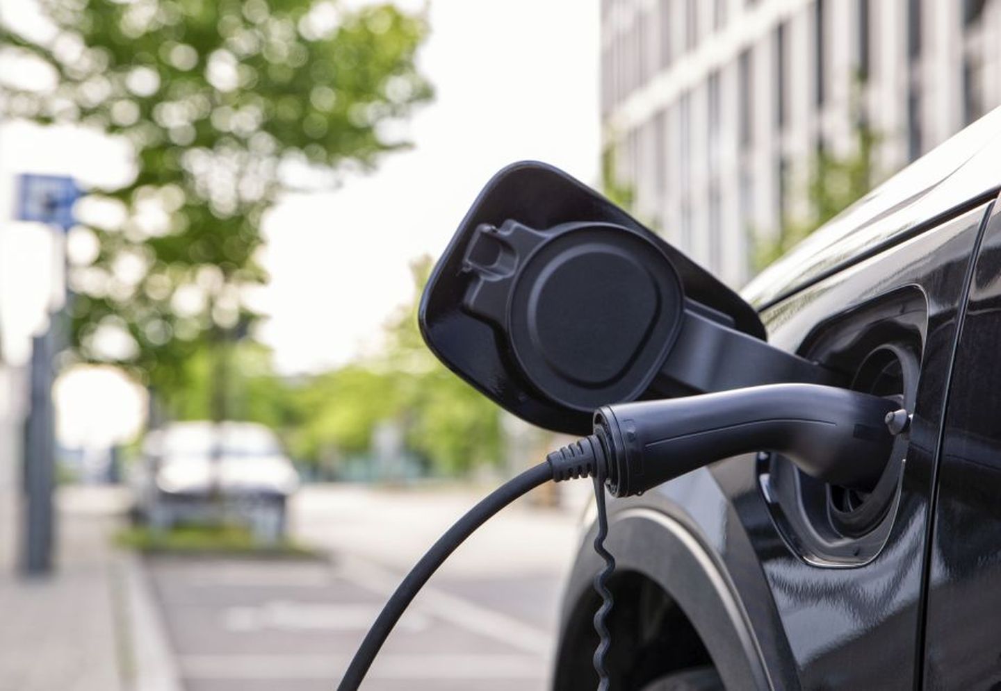 Nahaufnahme eines Elektroautos, das an eine Ladestation angeschlossen ist. © Westend61 via Getty Images