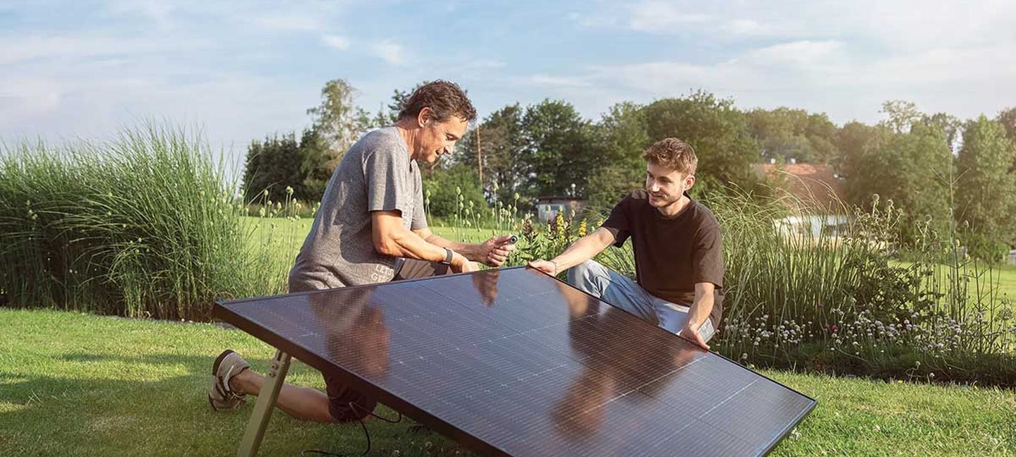 Zwei Männer stellen ein Balkonkraftwerk im Garten auf. © solago
