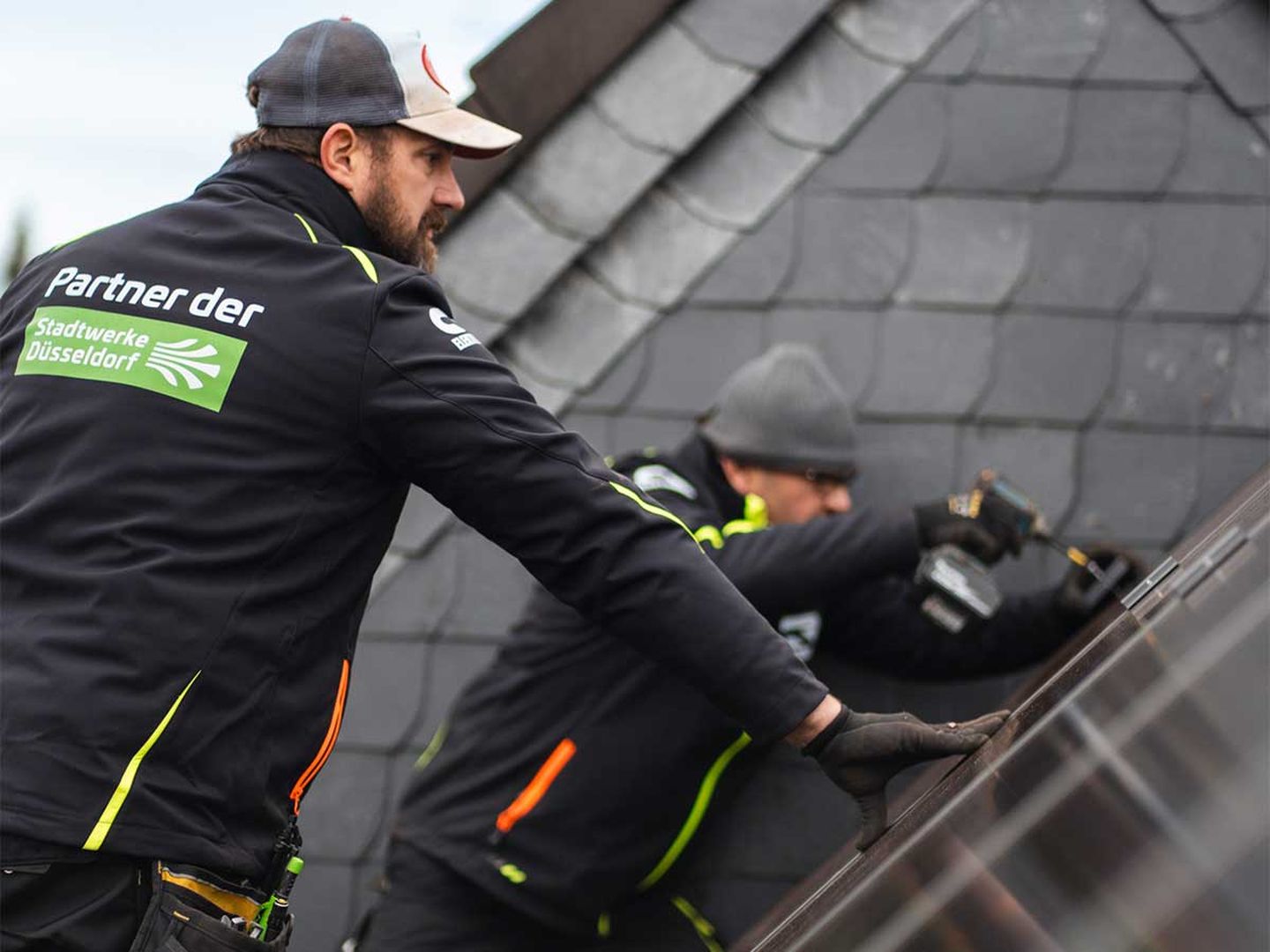 Zwei Dachdecker bei der Montage einer PV-Anlage auf dem Dach