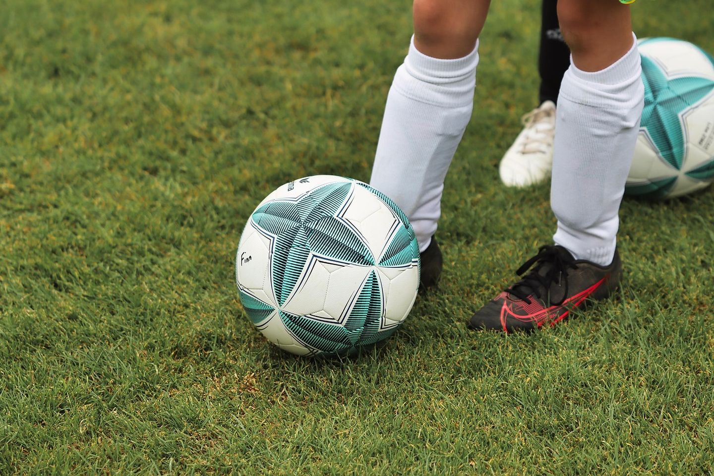 Ein Fußball auf einem Rasen mit zwei Füßen