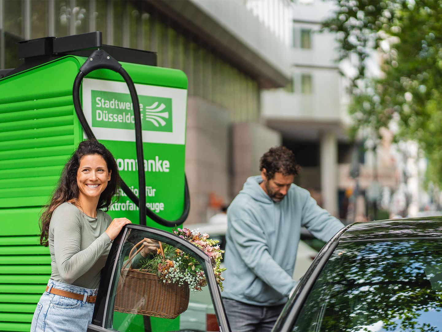 Eine Frau und ein Mann kommen nach dem Einkaufen zu ihrem ladenden E-Auto zurück