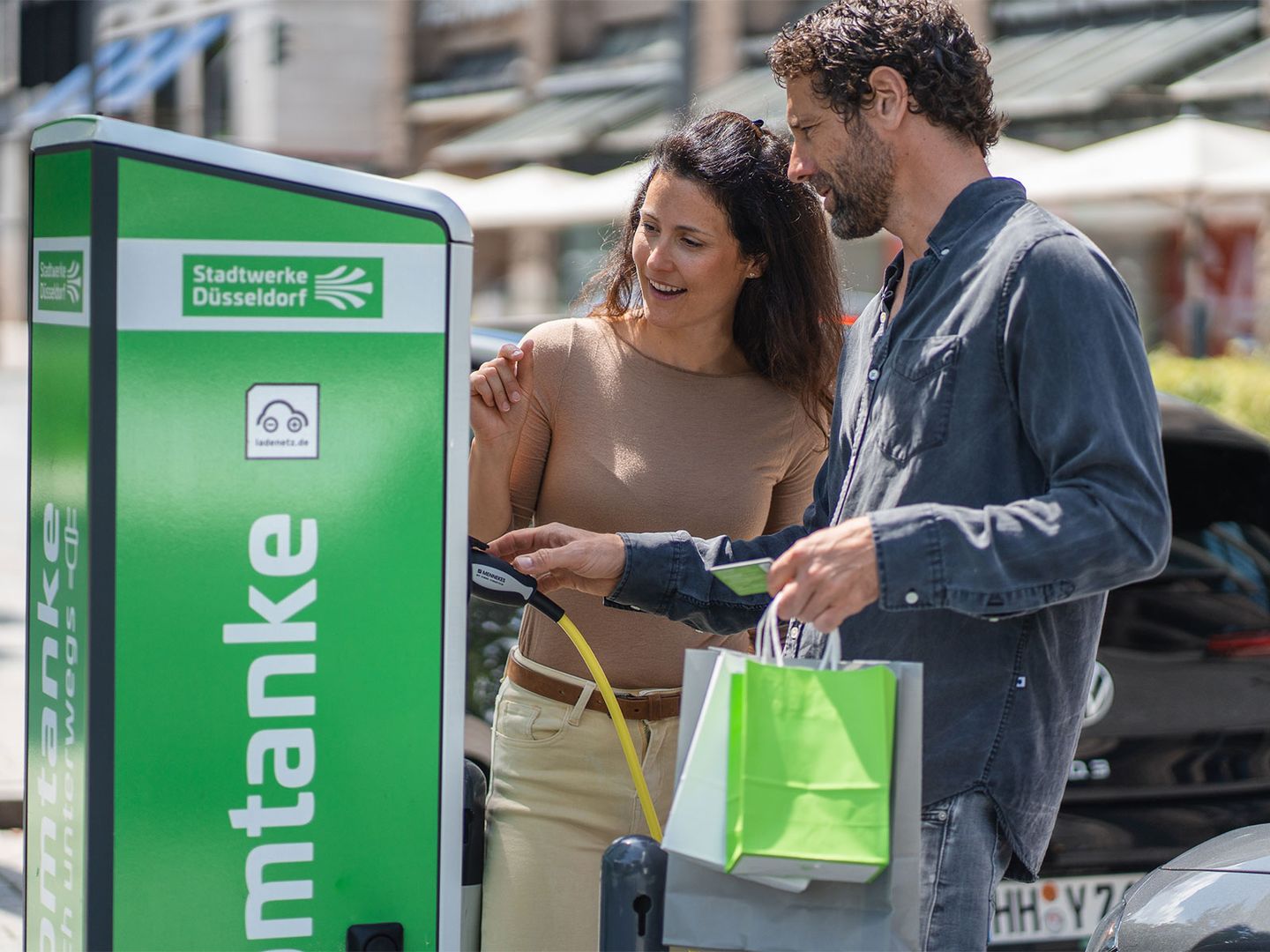 Ein Pärchen kommt nach dem Einkaufen zur Ladesäule der Stadtwerke Düsseldorf zurück