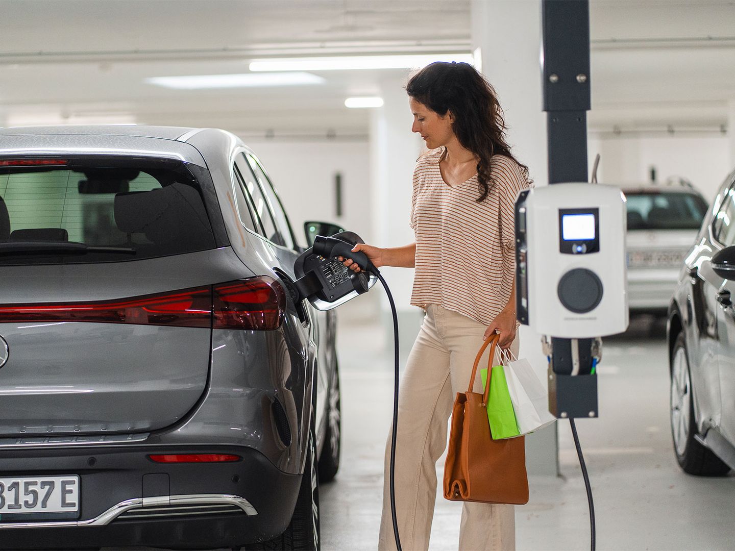Eine Frau lädt in einer Tiefgarage ihr E-Auto an einer Wallbox