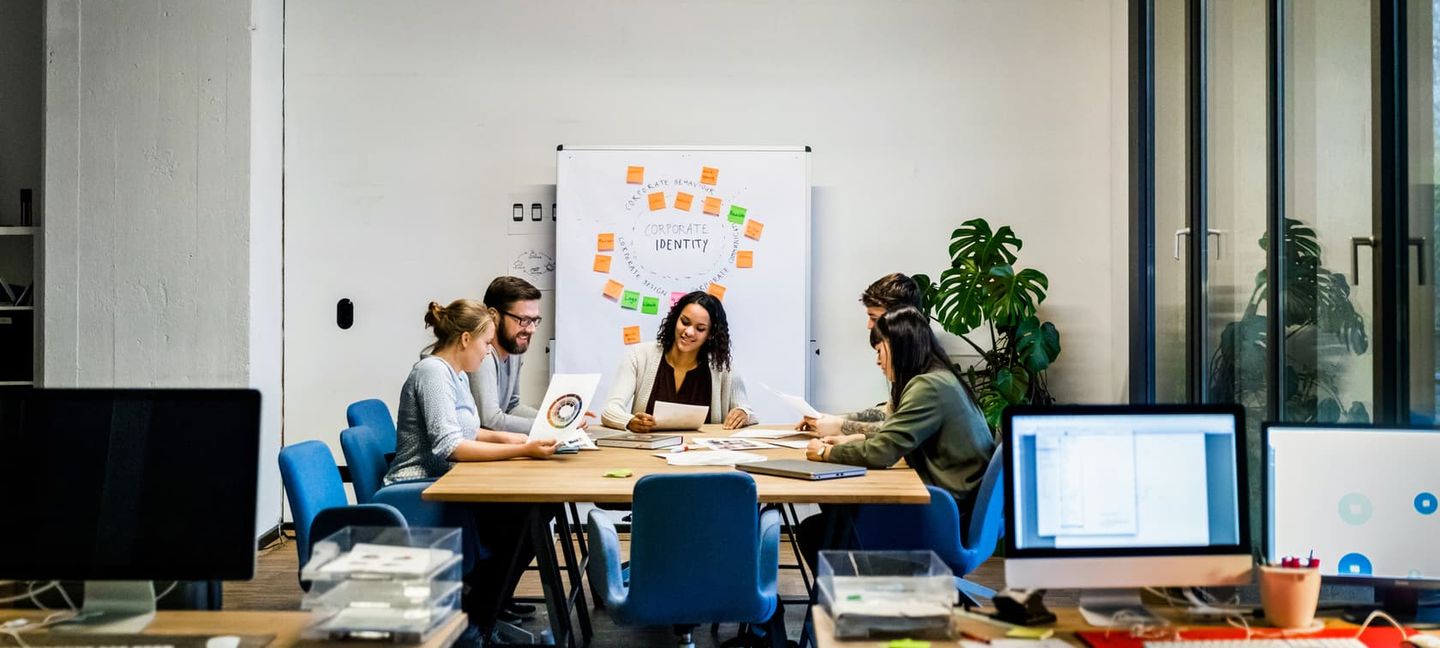 Kolleg:innen sitzen in einem Meetingraum und besprechen ein Projekt