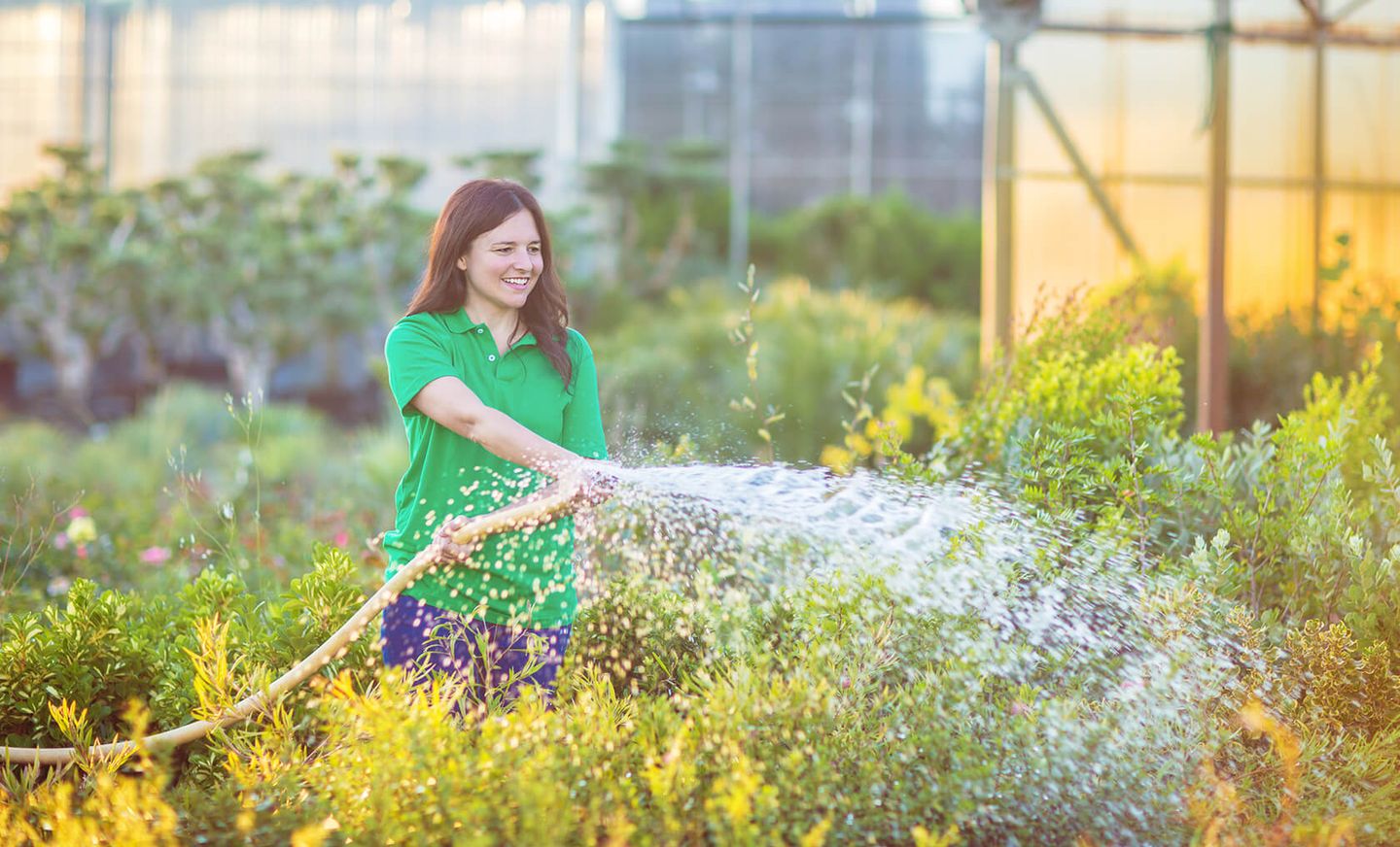 Eine Frau bewässert einen Garten mit einem Schlauch