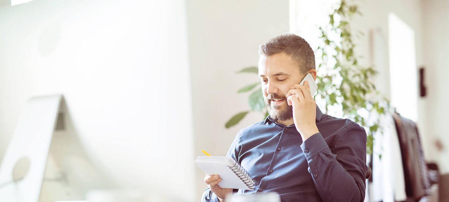 Ein Mann sitzt am PC und telefoniert