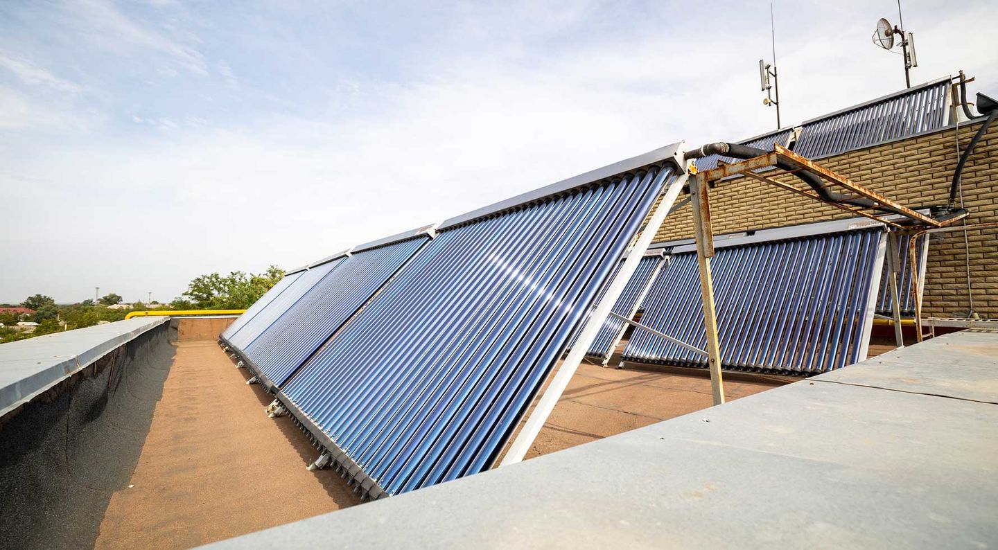 Photovoltaikanlage und zwei Solarthermie-Module auf einem Hausdach bei Sonnenschein. © MaYcaL / iStock / Getty Images Plus / via Getty Images