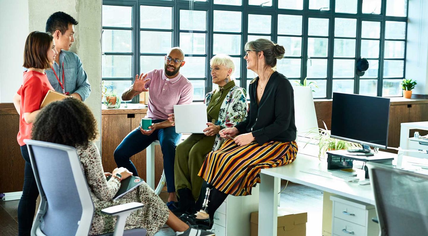 Kolleg:innen verschiedener Altersklassen führen im Büro ein angeregtes Gruppengespräch. © 10‘000 Hours / DigitalVision via Getty Images