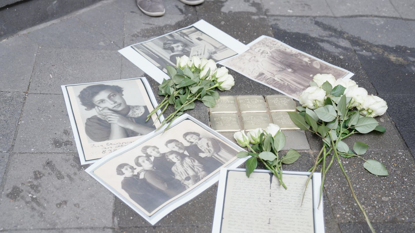 Schwarz-Weiß-Fotografien und weiße Rosen liegen um Stolpersteine verteilt auf dem Gehweg. © Stadtwerke Düsseldorf © Stadtwerke Düsseldorf
