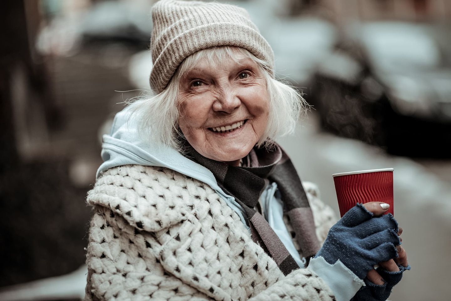 Eine alte Dame mit Becher lächelt in die Kamera