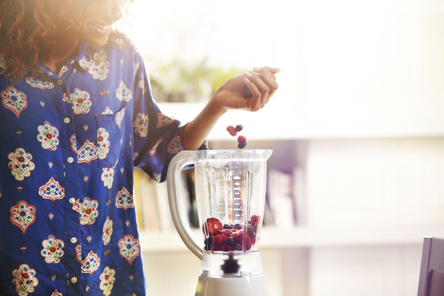 Eine Frau gibt verschiedene Beeren in einen Mixer. © Ezra Bailey / Stone via Getty Images