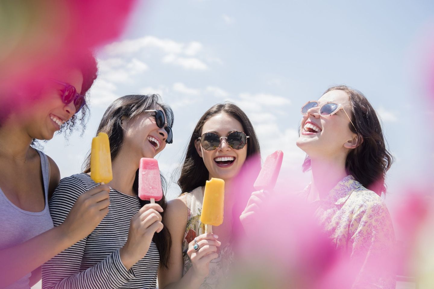 Eine Gruppe von vier Frauen genießt an einem sonnigen Tag buntes Wassereis am Stiel. © JGI/Jamie Grill / Tetra images via Getty Images © JGI/Jamie Grill / Tetra images via Getty Images