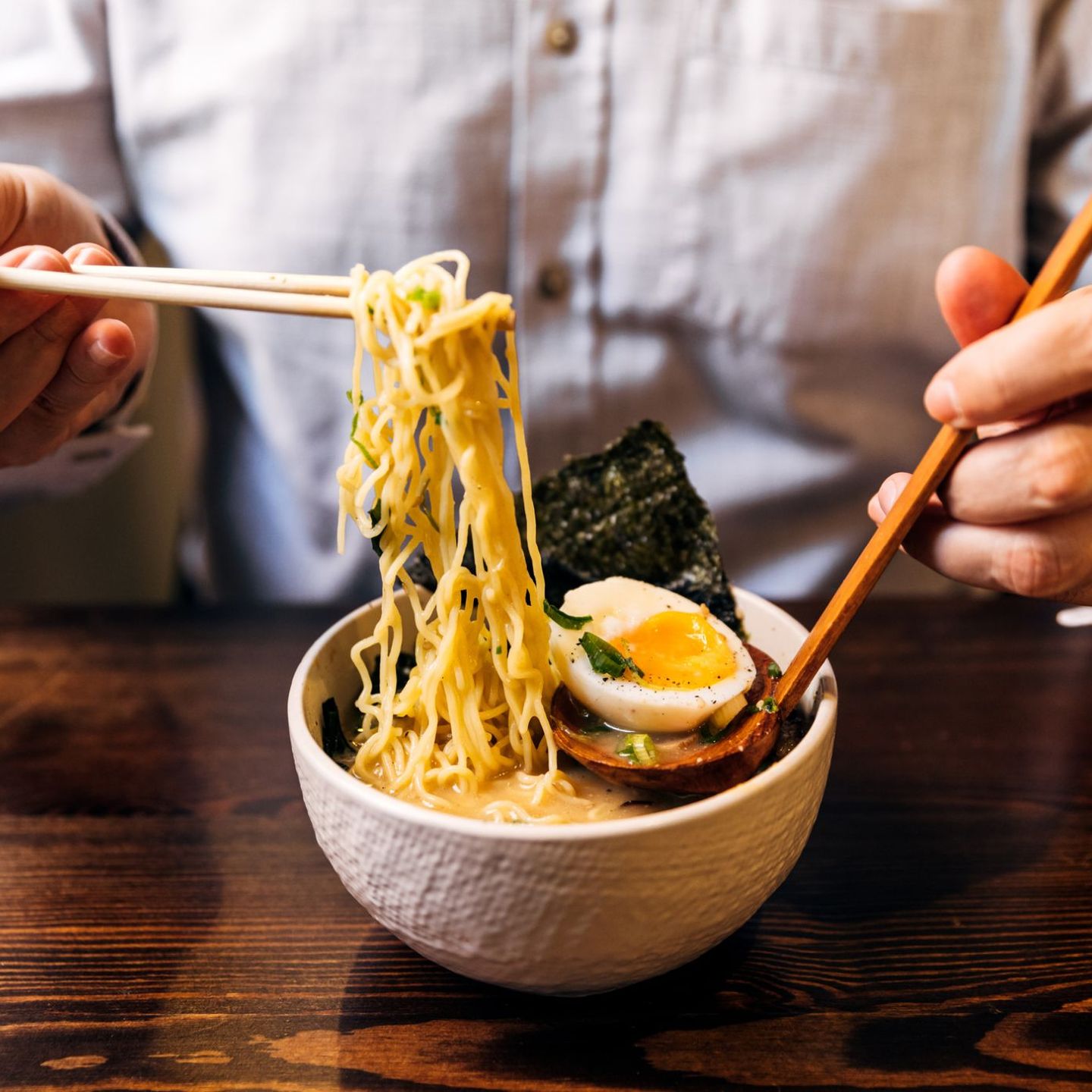 Nahaufnahme eines Mannes, der eine Ramen-Suppe isst. © Alexander Spatari / Moment via Getty Images
