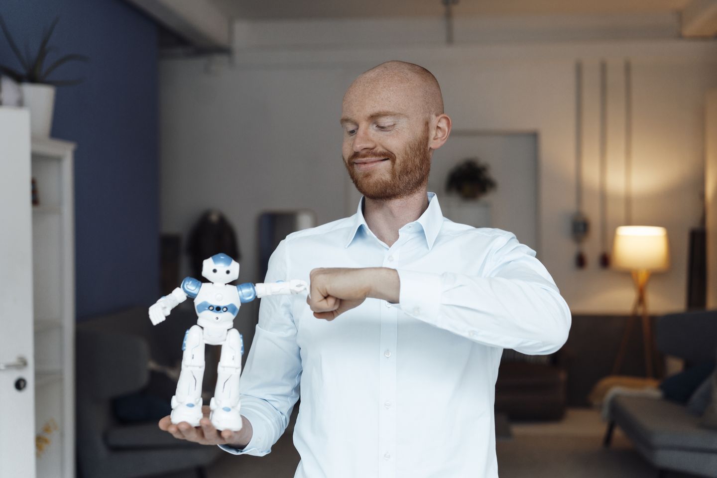 Geschäftsmann mit Spielzeugroboter im Homeoffice. © Westend61 / Westend61 via Getty Images