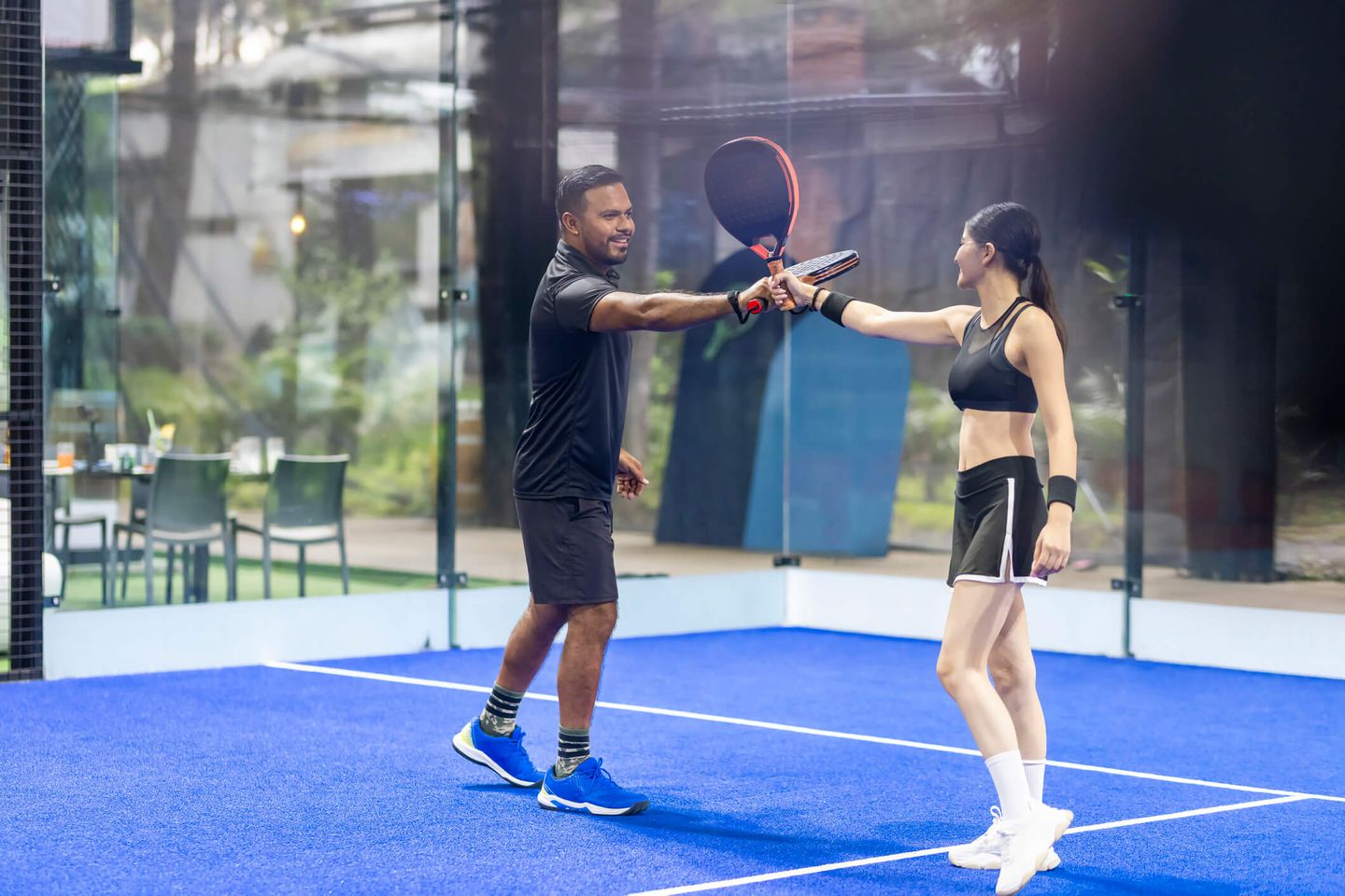 Ein Mann und eine Frau stoßen Padel-Schläger an © Arturo Peña Romano Medina / E+ via Getty Images
