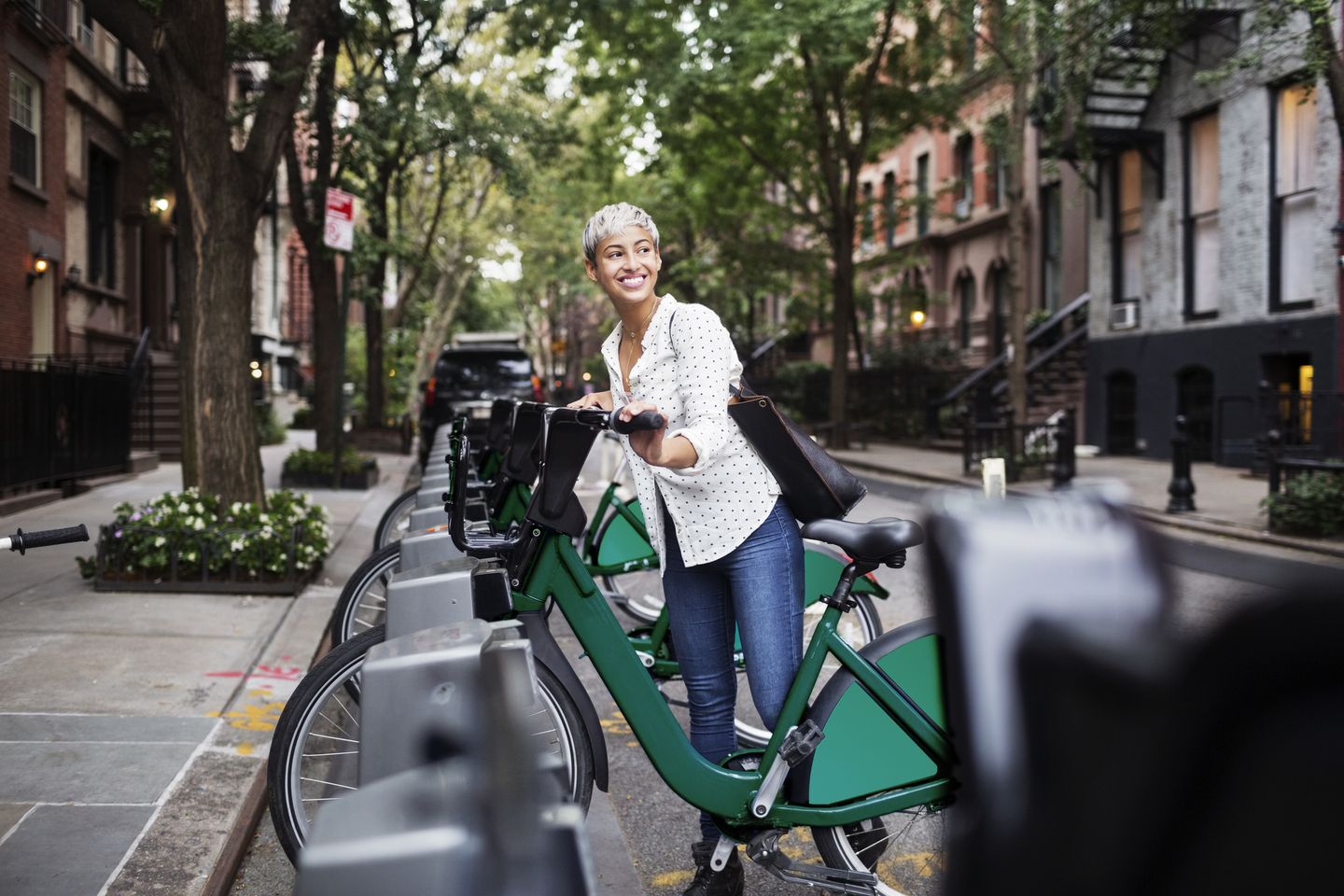 Eine junge Frau leiht ein Fahrrad an einer Sharing-Station. © Cavan Images / Cavan via Getty Images