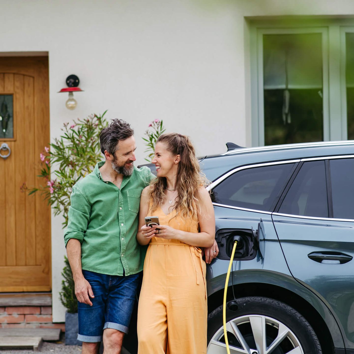 Ein junges Paar lädt sein E-Auto vor der eigenen Haustür. © Halfpoint Images via Getty Images