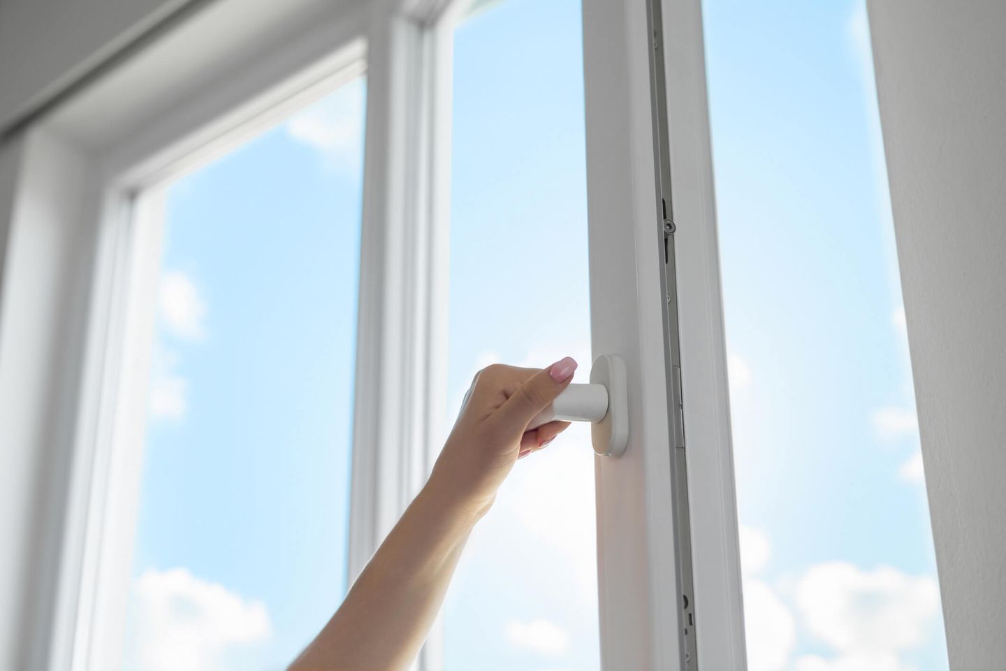 Eine Frauenhand öffnet ein Fenster