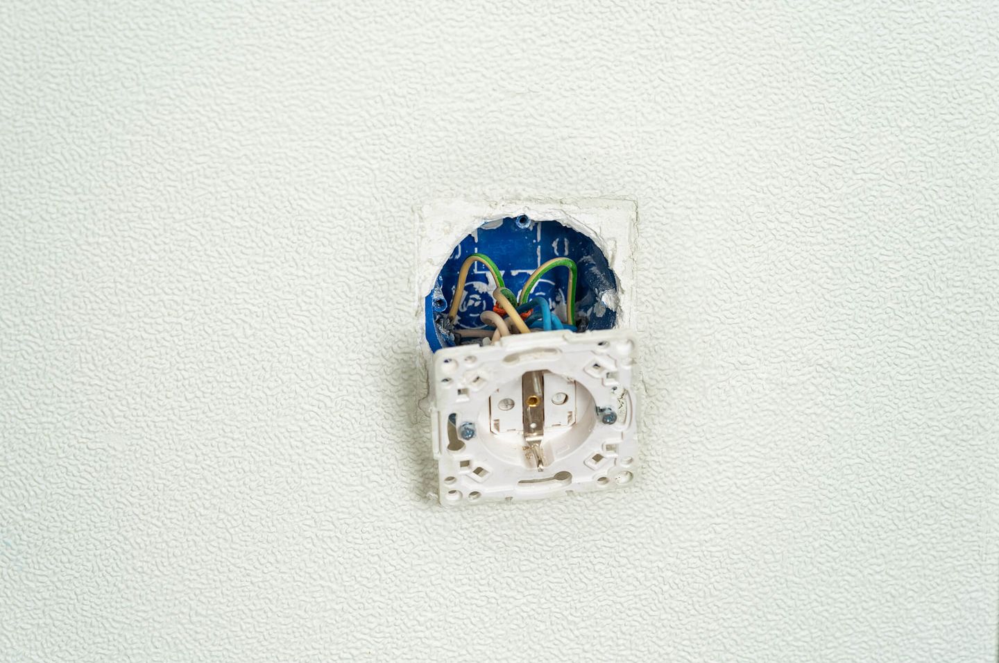 Eine Steckdose wird installiert, das Gehäuse hängt vor bunten Kabeln an der Wand. © Belkina Margarita / iStock Getty Images Plus via Getty Images © Belkina Margarita / iStock Getty Images Plus via Getty Images