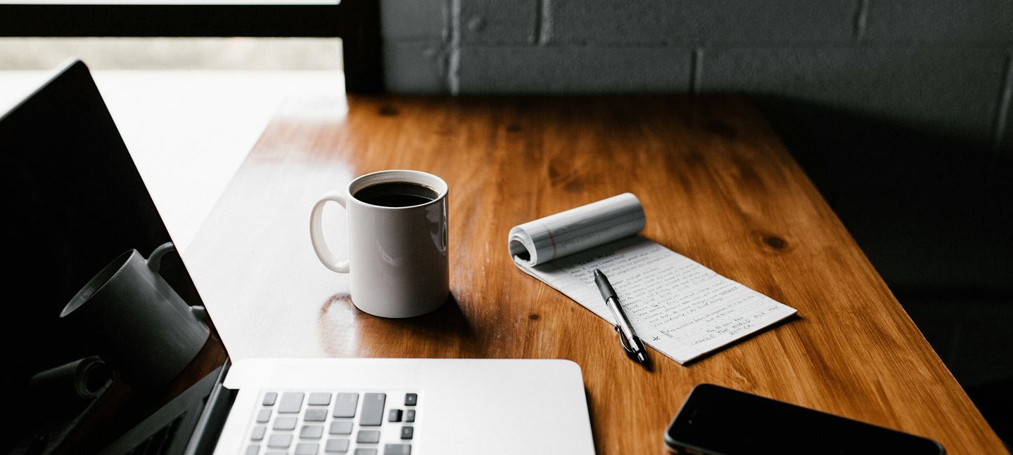 MacBook Pro, weißer Keramikbecher und schwarzes Smartphone auf dem Tisch @andrewtneel via via Unsplash
