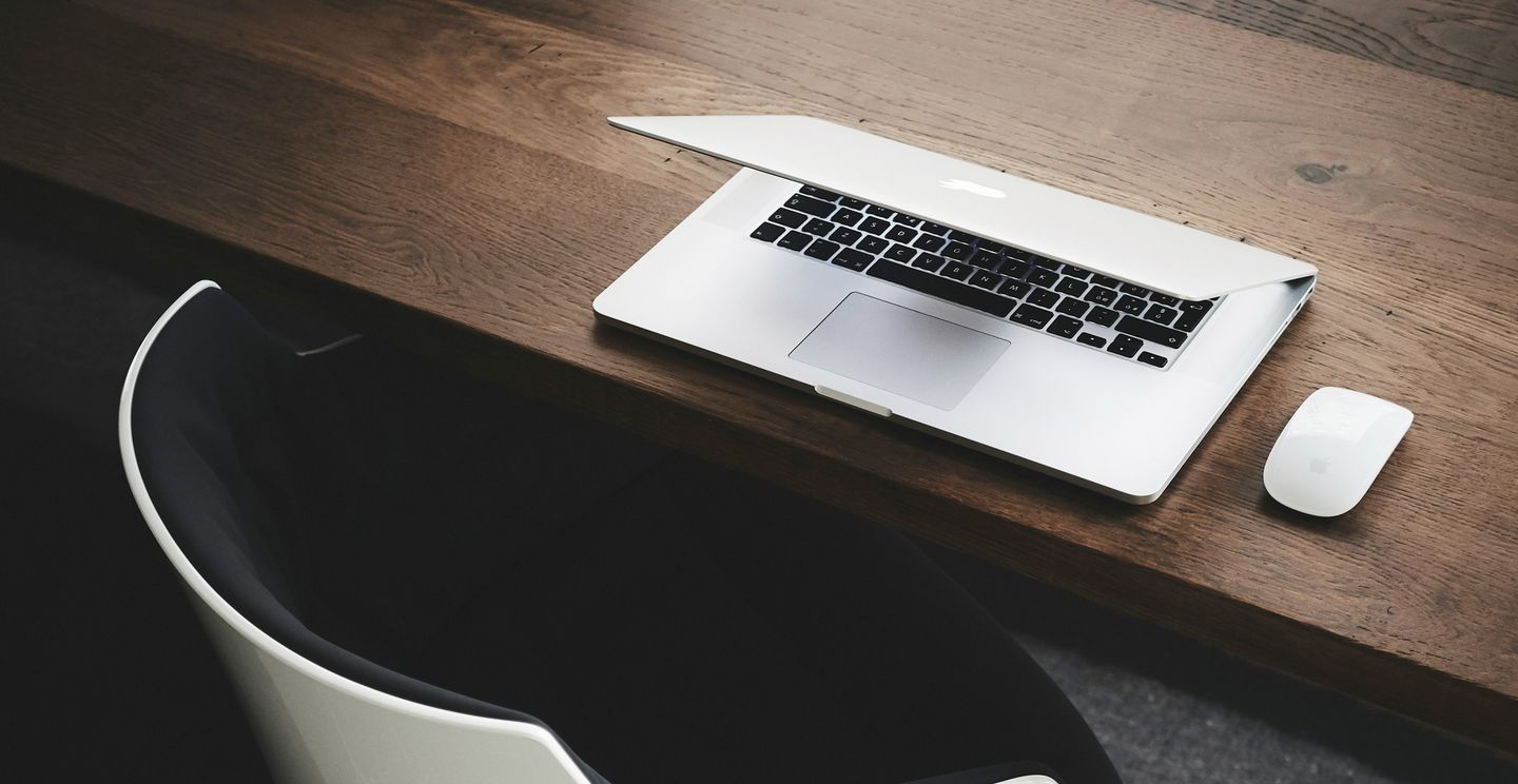 Macbook und Maus auf einem Tisch