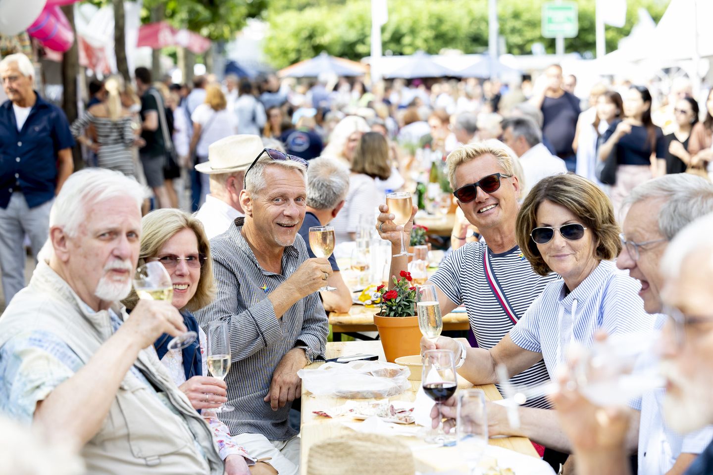 Gäste sitzen an einer Biertischgarnitur und verkosten Wein und Champagner. © Destination Düsseldorf Veranstaltungs GmbH / Wellfairs GmbH via www.duesseldorfer-frankreich-fest.de