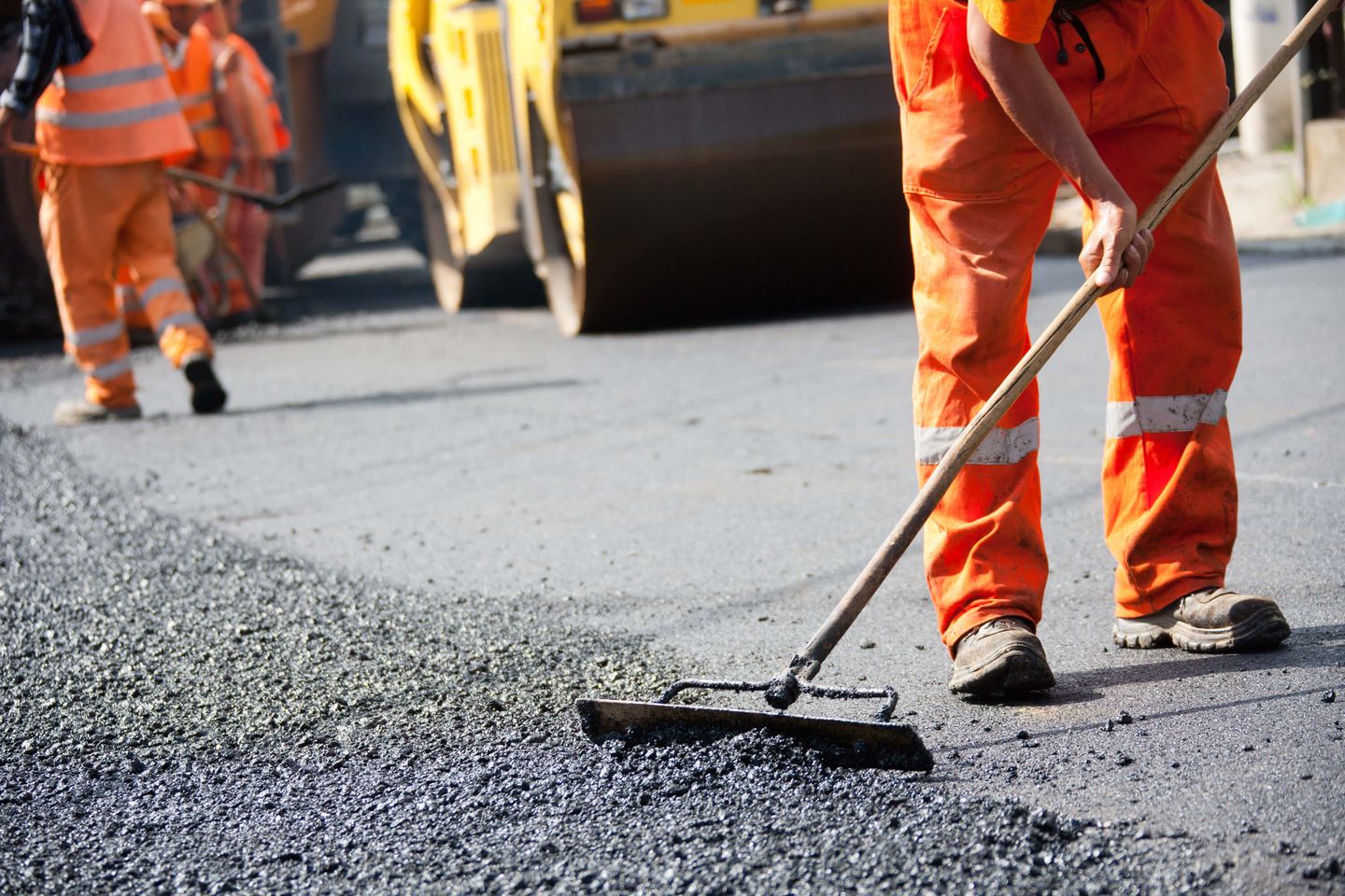 Ein Arbeiter verteilt Kies auf einer Baustelle.