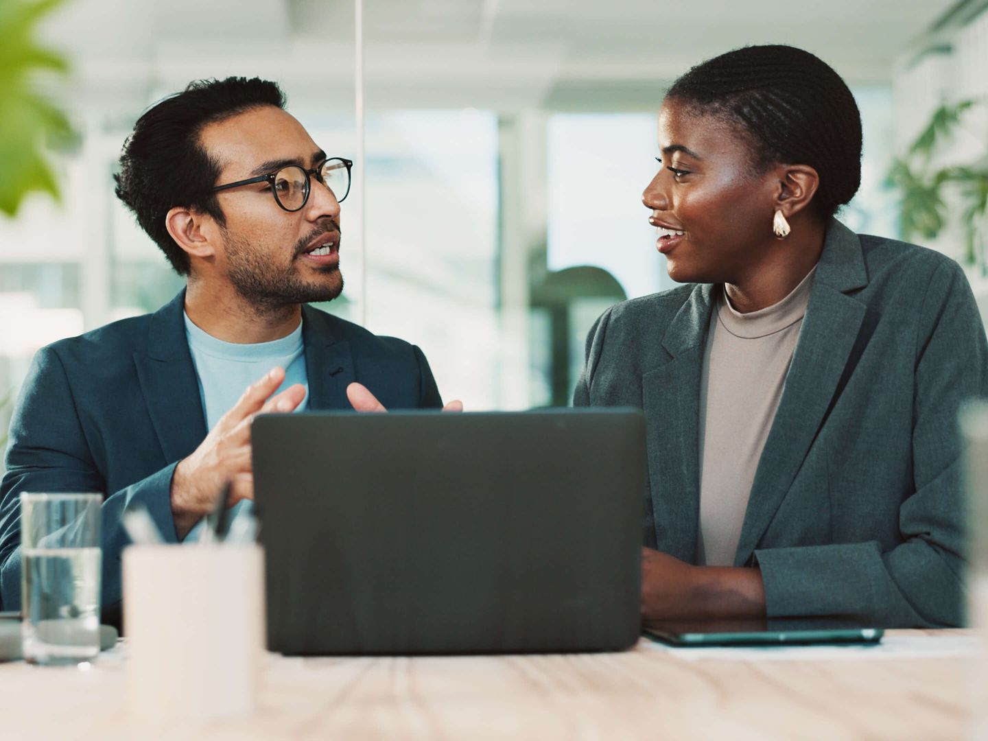 Zwei Personen im Business-Outfit führen ein Gespräch in moderner Büroumgebung. © Jacob Wackerhausen / iStock / Getty Images Plus via Getty Images