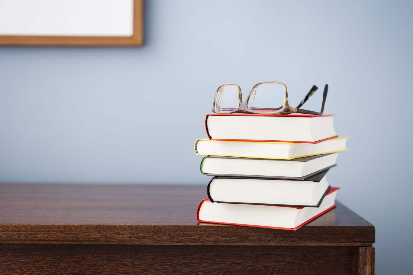 Gestapelter Bücherstapel mit Brille auf Holzschreibtisch Getty