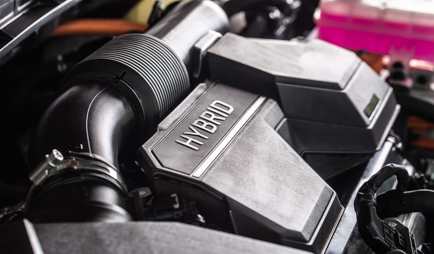 Nahaufnahme eines Hybridmotors mit deutlich sichtbarer Beschriftung „HYBRID“. Getty