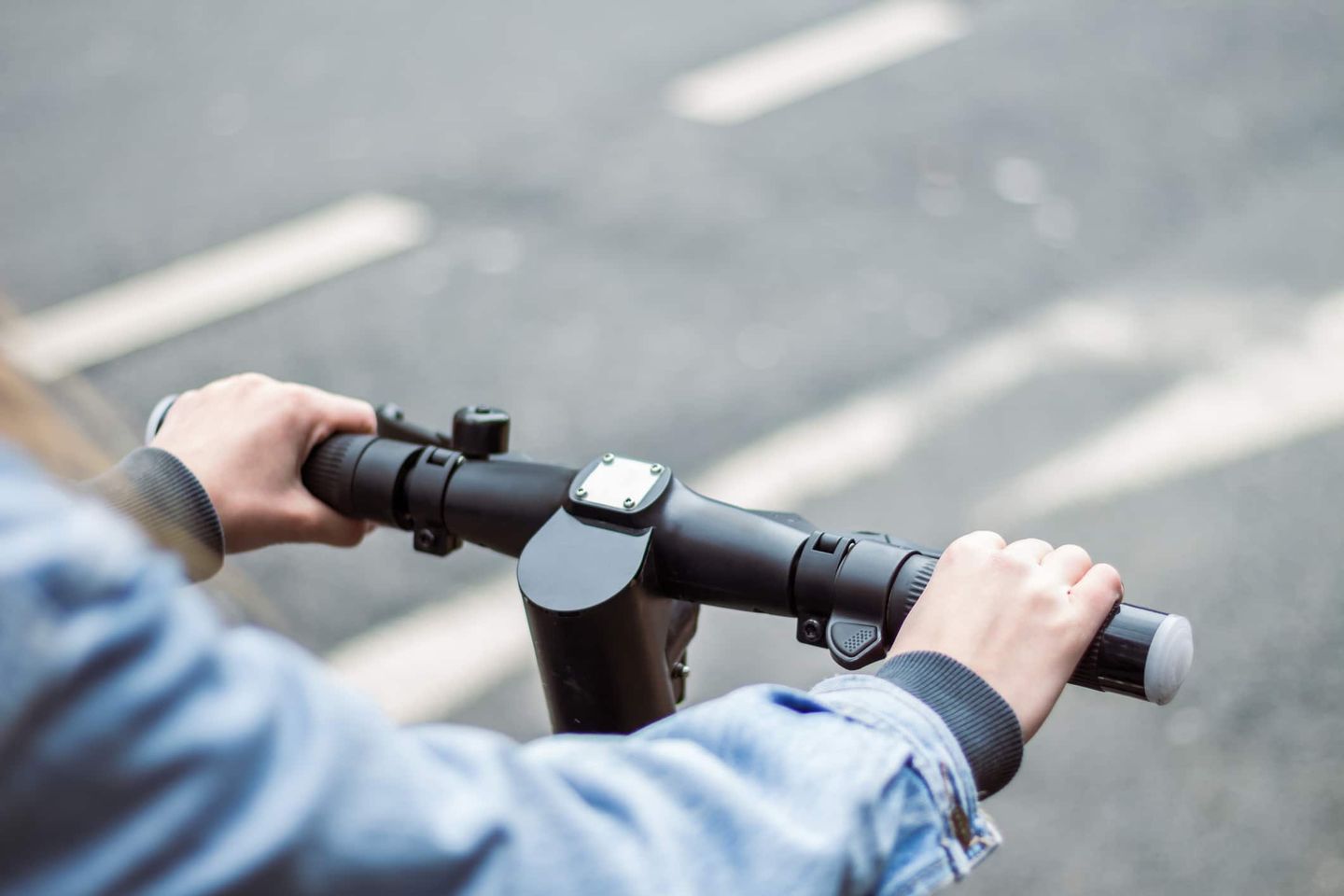 Nahaufnahme von Händen am Lenker eines E-Scooters. Getty