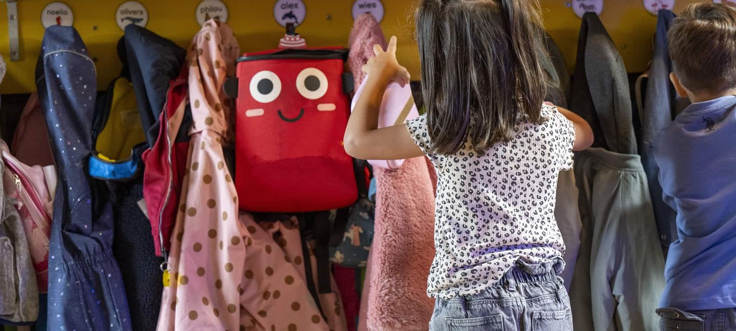 Kinder hängen ihre Jacken in einer Kindergarderobe auf, über der kleine Namensschilder angebracht sind. Getty