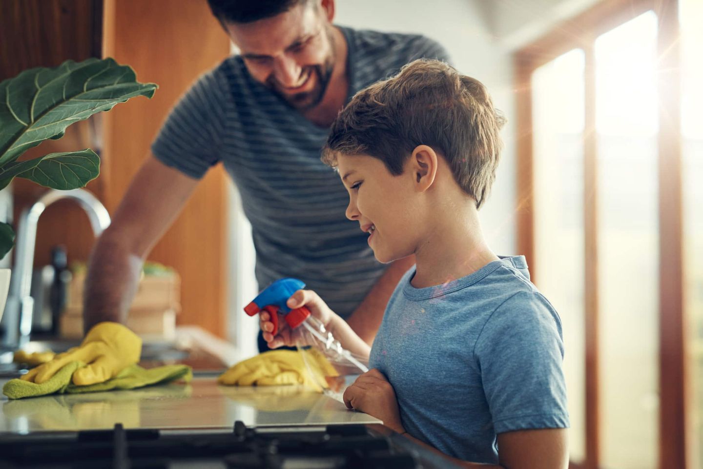 Vater und Sohn putzen gemeinsam in der Küche. Getty