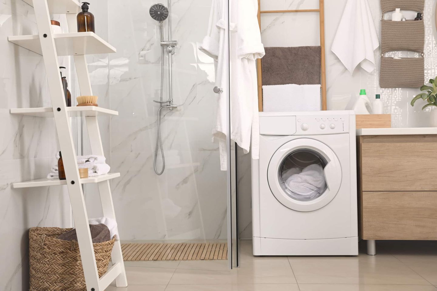 Badezimmer mit Dusche, Waschmaschine und Leiterregal zur Aufbewahrung. Getty