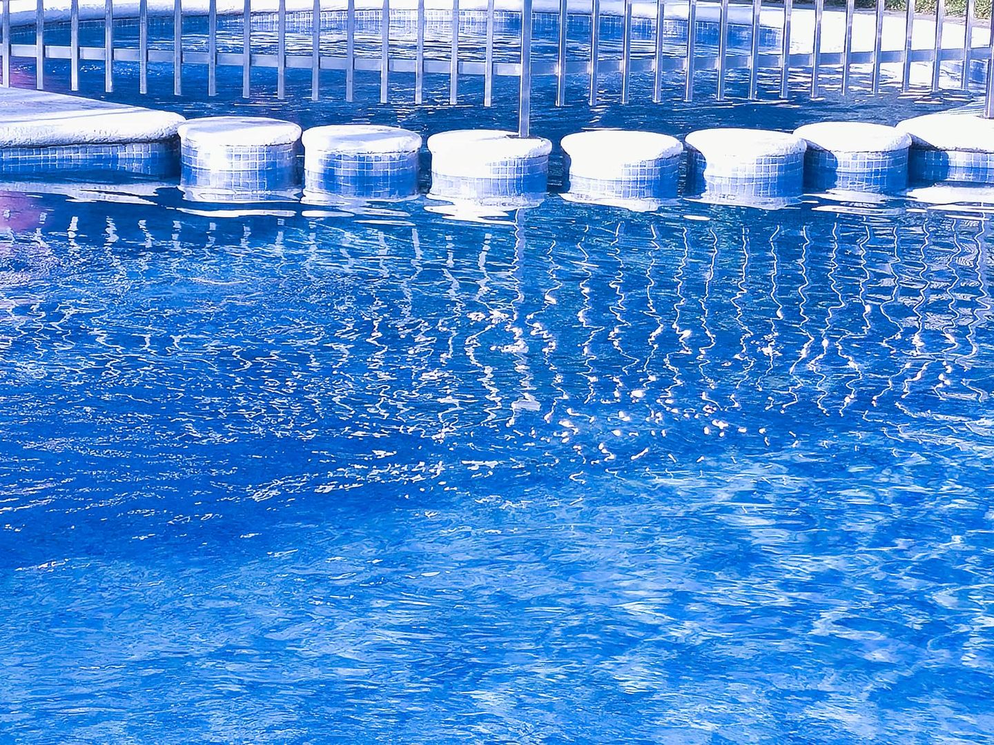 Schwimmbad mit blauen Fliesen und runden Sitzstufen im Wasser Getty