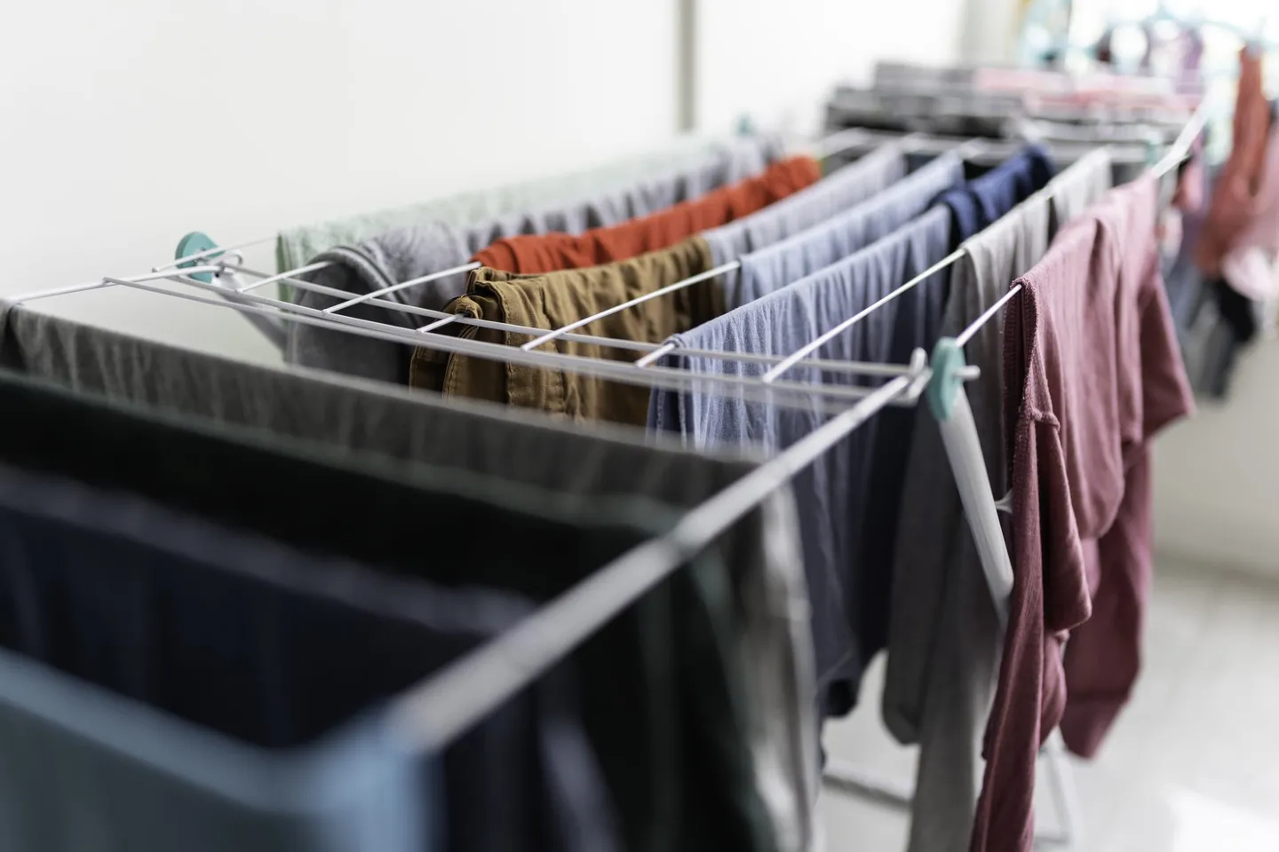 Nahaufnahme eines Wäscheständers mit frisch gewaschener Kleidung in verschiedenen Farben.
